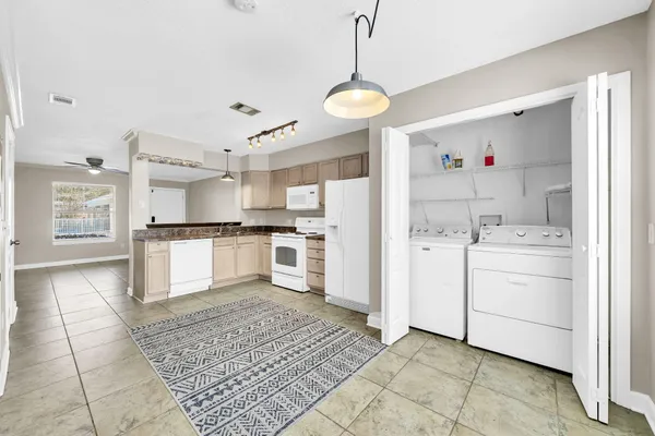 a kitchen with granite countertop a refrigerator a stove and white cabinets with wooden floor