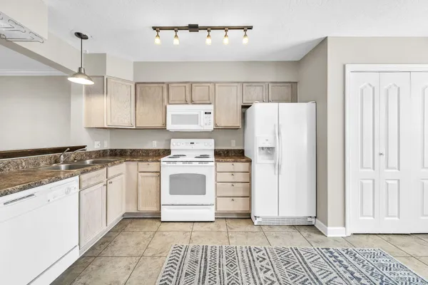 a kitchen with granite countertop a refrigerator and white cabinets