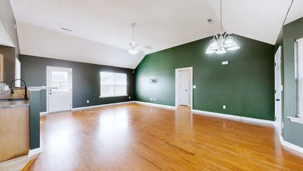 a view of an empty room with wooden floor and a fireplace
