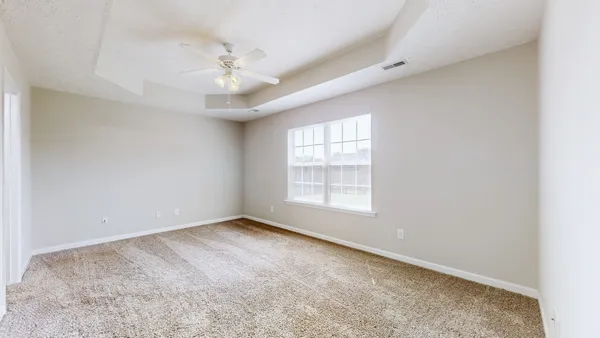 an empty room with a ceiling fan and window