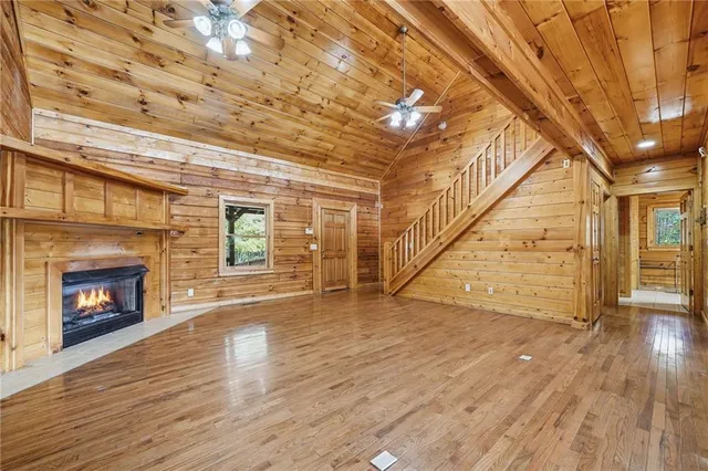 an empty room with wooden floor fireplace and windows
