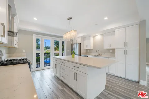 a large kitchen with kitchen island a stove a sink dishwasher and white cabinets with wooden floor