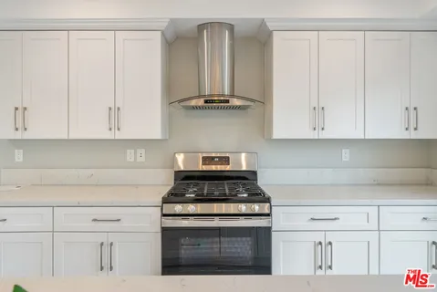 a kitchen with stainless steel appliances granite countertop white cabinets and a stove