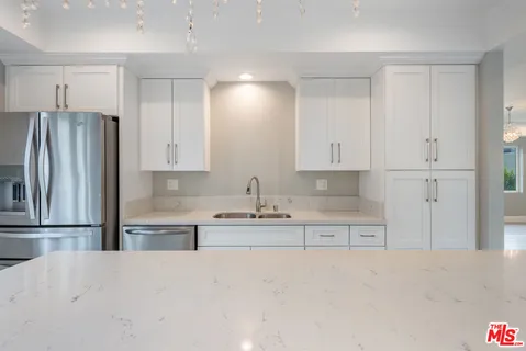 a kitchen with granite countertop white cabinets and stainless steel appliances