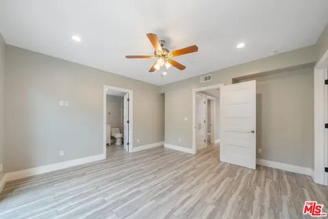 a view of empty room with wooden floor and fan
