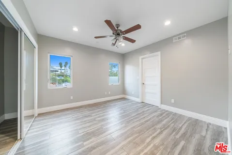 an empty room with wooden floor and ceiling fan