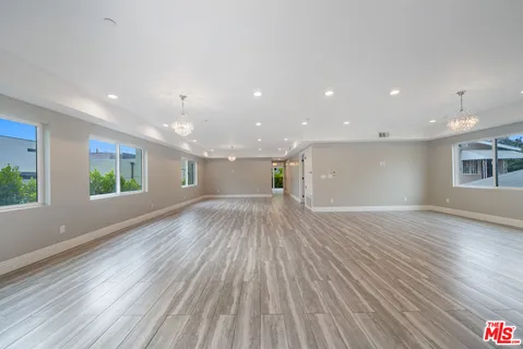 a view of empty room with wooden floor and windows
