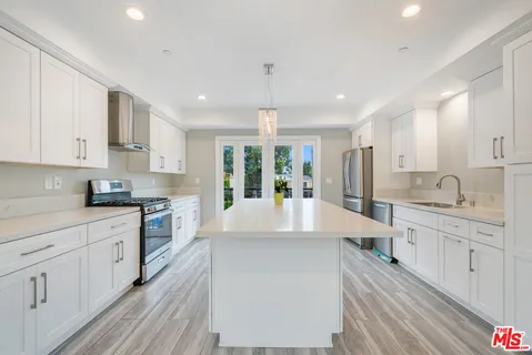 a large white kitchen with lots of counter space wooden floor and appliances