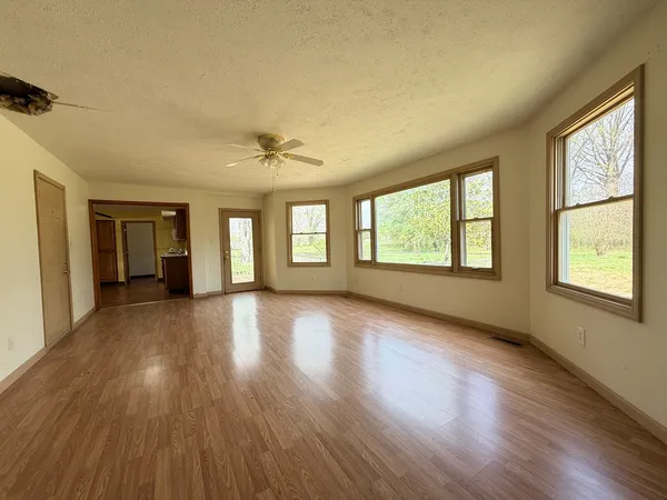 a view of an empty room with wooden floor and a window