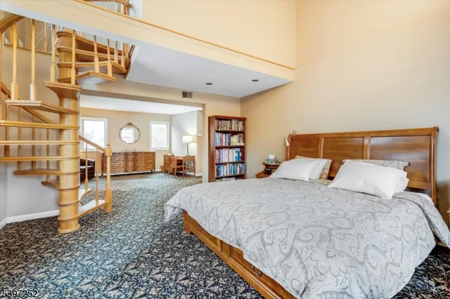 a spacious bedroom with a bed a table and bookshelf