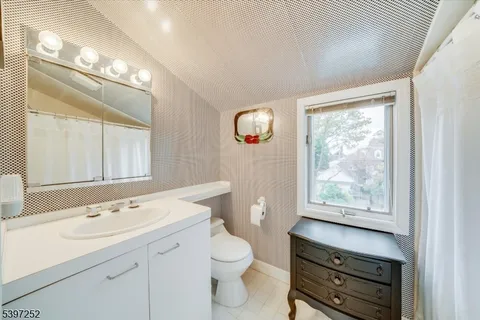 a bathroom with a toilet a sink a mirror and a window