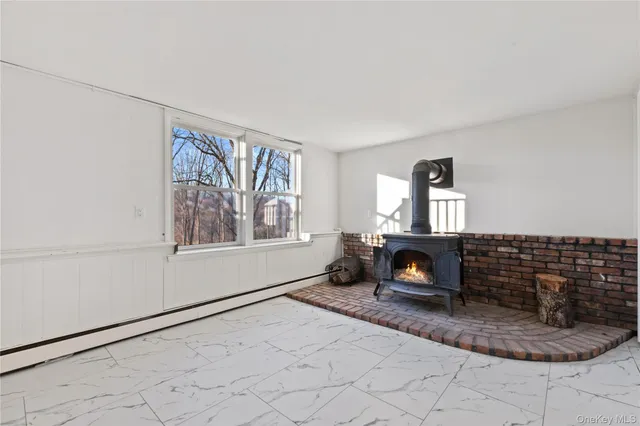 a view of an empty room with window and hardwood floor