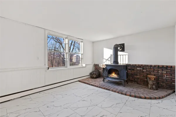a view of an empty room with window and hardwood floor