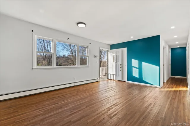 a view of an empty room with window and wooden floor
