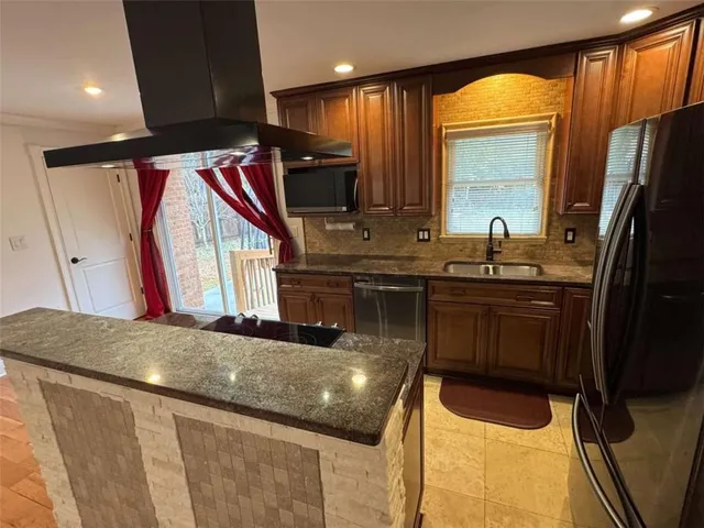 a kitchen with stainless steel appliances granite countertop a sink a stove and a refrigerator