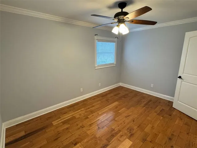 a view of an empty room with window and chandelier fan