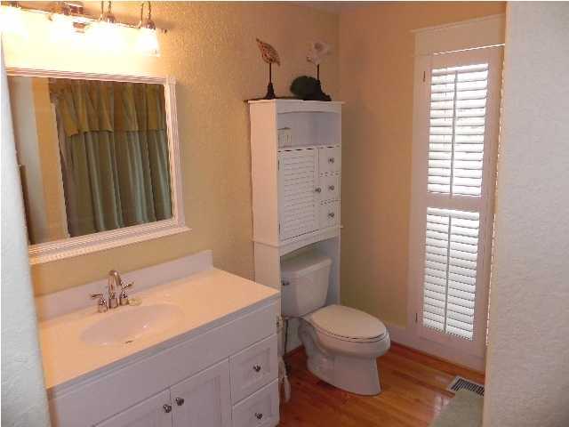 630 Blue Mountain Beach Road Santa Rosa Beach, FL 32459 - Photo 18 of 26 a bathroom with a granite countertop toilet a sink a mirror and a window