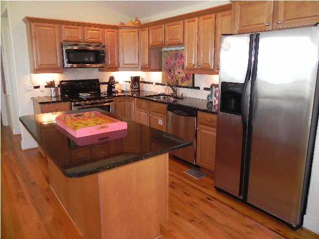 630 Blue Mountain Beach Road Santa Rosa Beach, FL 32459 - Photo 8 of 26 a kitchen with stainless steel appliances granite countertop a refrigerator a sink a stove a microwave and wooden cabinets