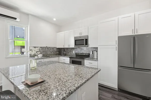 a kitchen with stainless steel appliances granite countertop a refrigerator a stove a sink and a counter space