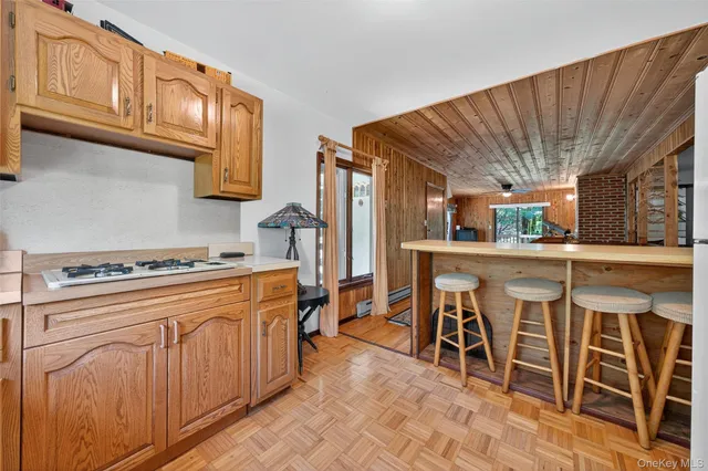 a kitchen with stainless steel appliances granite countertop a stove top oven a refrigerator a dining table and chairs with wooden floor