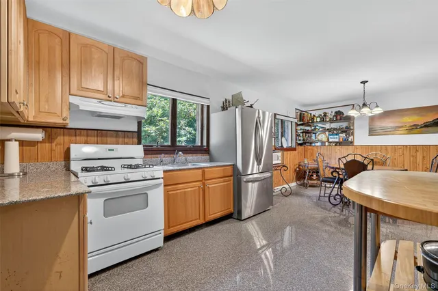 a kitchen with stainless steel appliances granite countertop a stove a sink dishwasher and a refrigerator with wooden cabinets