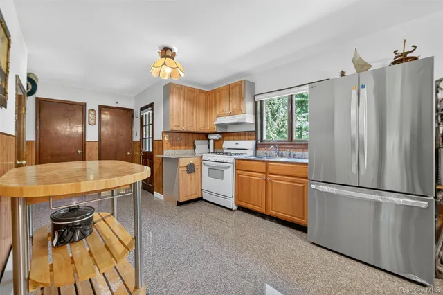 a kitchen with a refrigerator a sink dishwasher a stove and a dining table with wooden floor