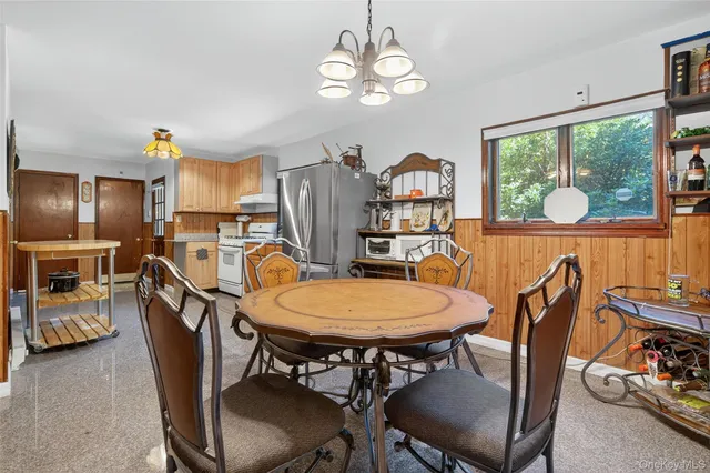 a view of a dining room with furniture a chandelier and large windows