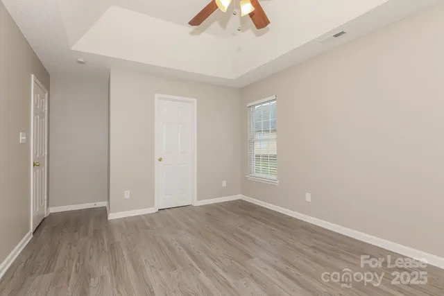 an empty room with wooden floor closet and fan