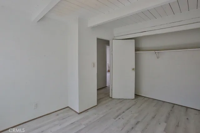 an empty room with wooden floor cabinet and windows