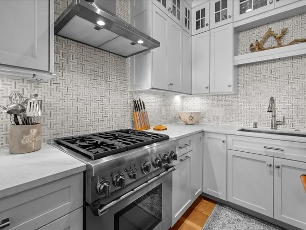 a kitchen with stainless steel appliances granite countertop a stove and a white cabinets