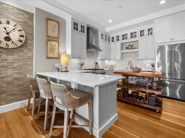 a kitchen with stainless steel appliances granite countertop a stove top oven a refrigerator a sink and dishwasher with wooden floor