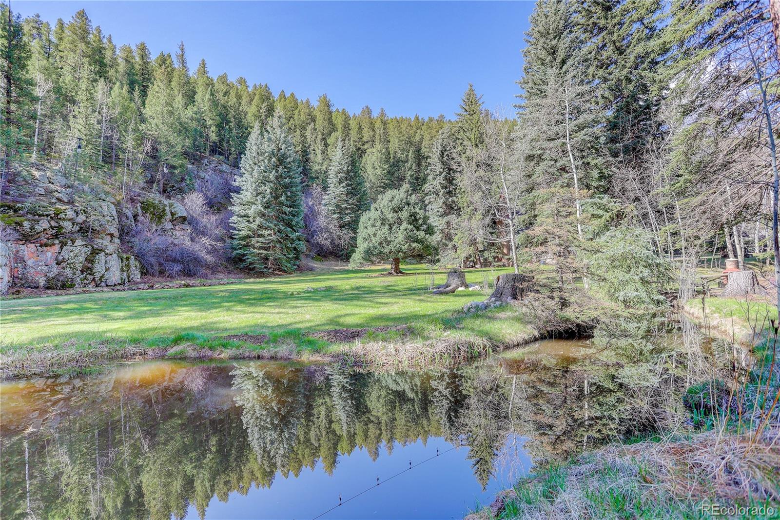 1730 Upper Bear Creek Road Evergreen, CO 80439 - Photo 11 of 40 a view of a lake with a yard and large trees