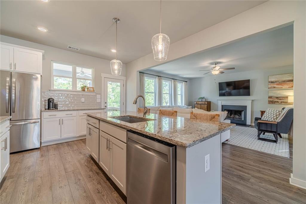 4070 Links Boulevard Jefferson, GA 30549 - Photo 11 of 46 a kitchen with granite countertop a stove a sink a refrigerator and white cabinets with wooden floor