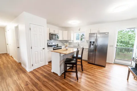 a kitchen with stainless steel appliances a dining table chairs refrigerator and sink