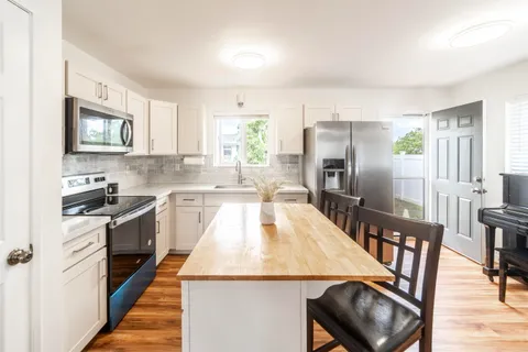 a large kitchen with a stove a sink dishwasher a microwave oven with cabinets and wooden floor