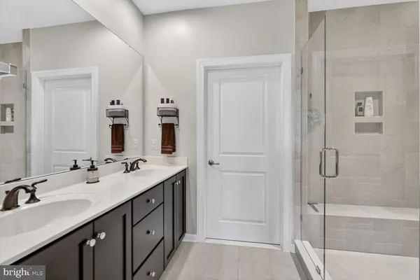 a bathroom with a double vanity sink mirror and shower