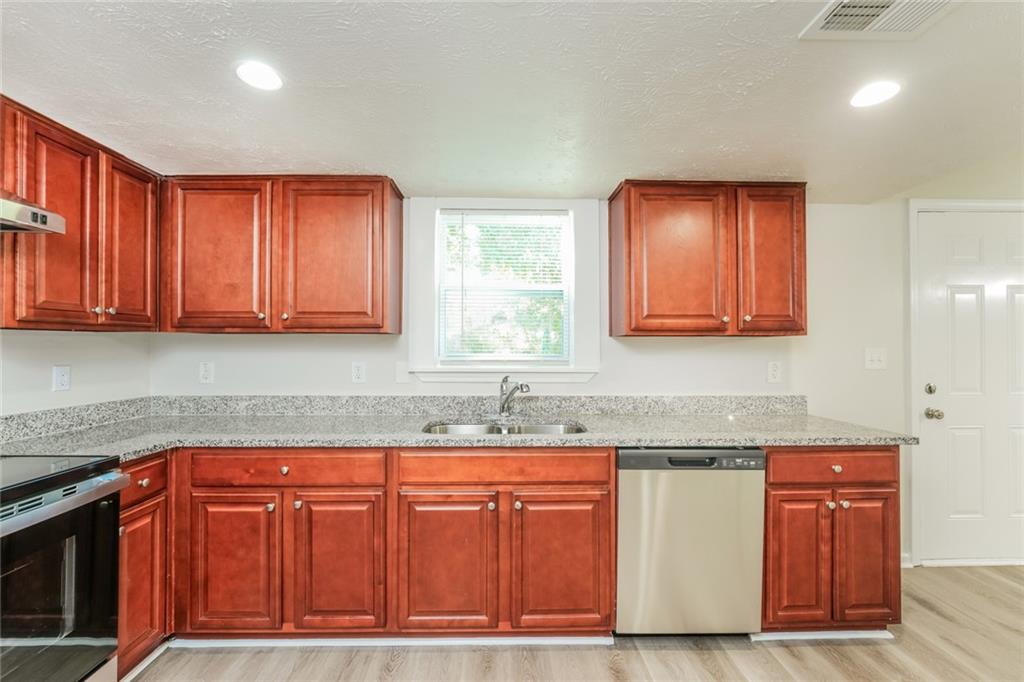 884 3rd Street Stone Mountain, GA 30083 - Photo 13 of 26 a kitchen with granite countertop wooden cabinets a sink and dishwasher