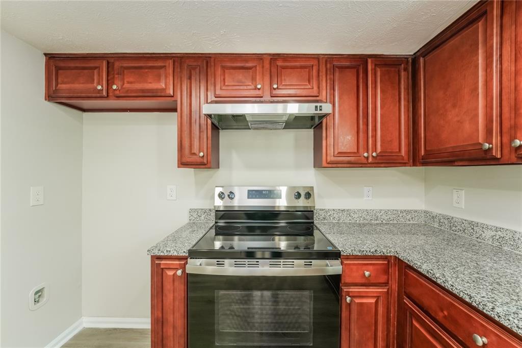 884 3rd Street Stone Mountain, GA 30083 - Photo 14 of 26 a kitchen with stainless steel appliances granite countertop a stove and a microwave