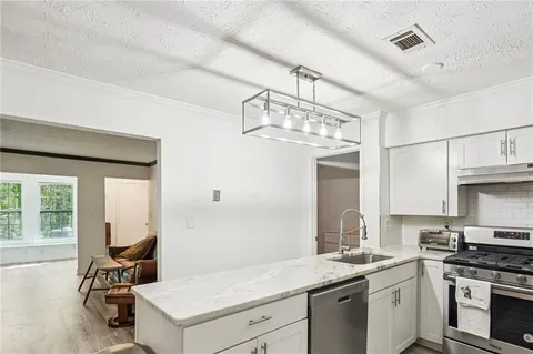 a kitchen with a sink dishwasher a stove and a chandelier