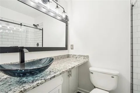 a bathroom with a granite countertop sink a toilet and a mirror