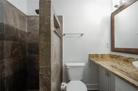 a bathroom with a granite countertop sink toilet and shower