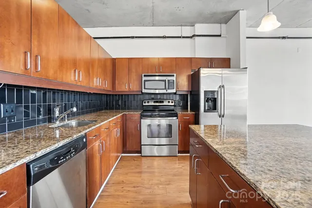 a kitchen with stainless steel appliances granite countertop a sink a stove and a refrigerator