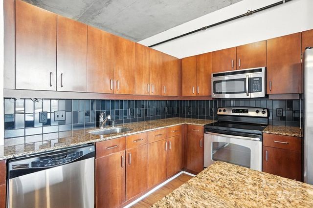 a kitchen with stainless steel appliances granite countertop a stove a sink and a microwave