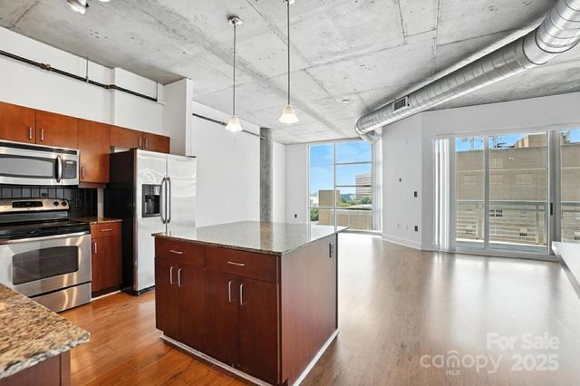 a kitchen with stainless steel appliances granite countertop a refrigerator a sink dishwasher a kitchen island with wooden cabinets and floor