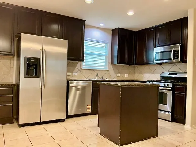 a kitchen with granite countertop a refrigerator and a stove top oven