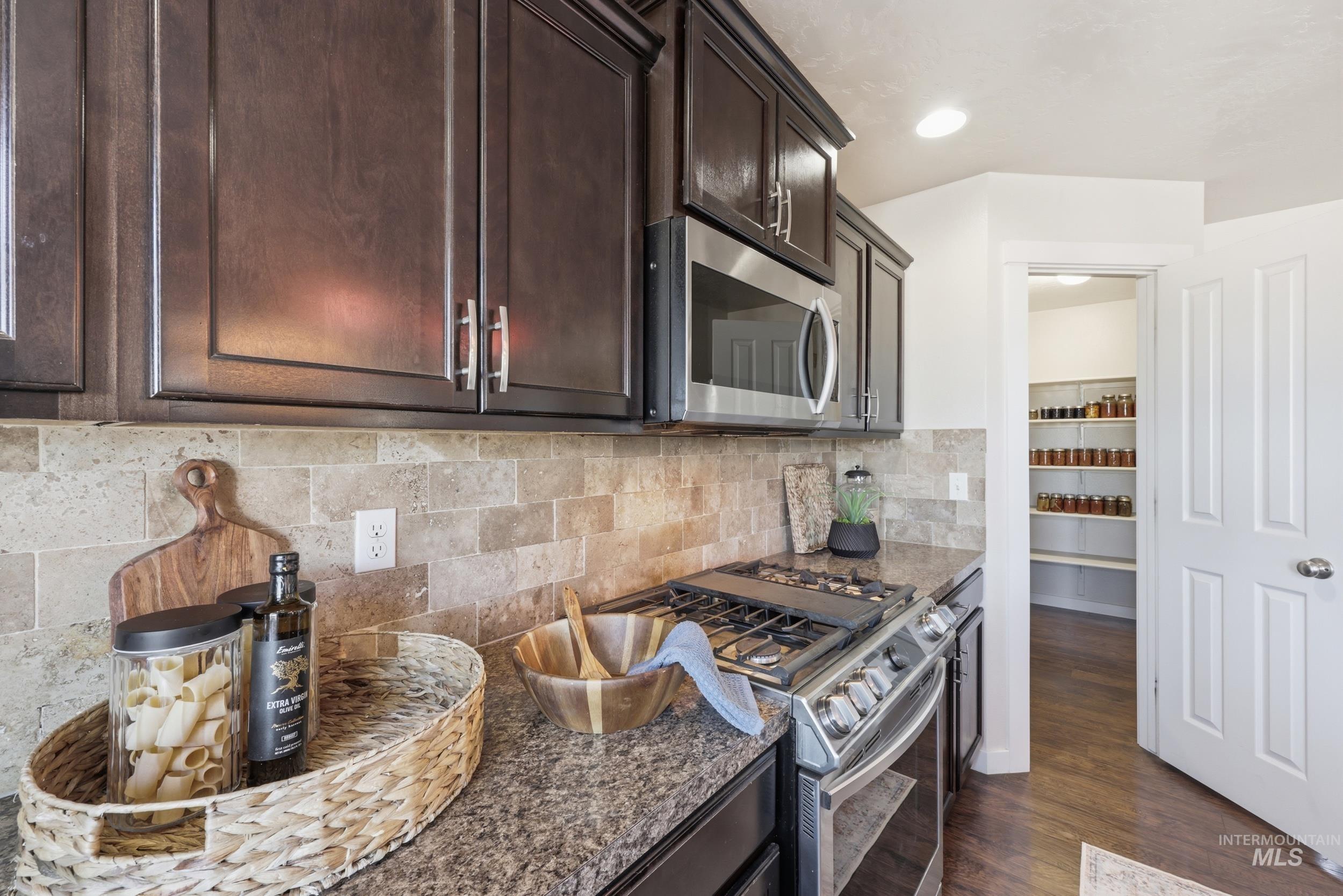 4855 South Chex Way Boise, ID 83709 - Photo 34 of 47 Kitchen featuring dark wood cabinetry, a tiled backsplash, and granite-style countertops