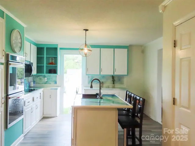 a kitchen with stainless steel appliances granite countertop a sink a stove and a wooden floors
