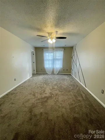 a view of an empty room and chandelier fan