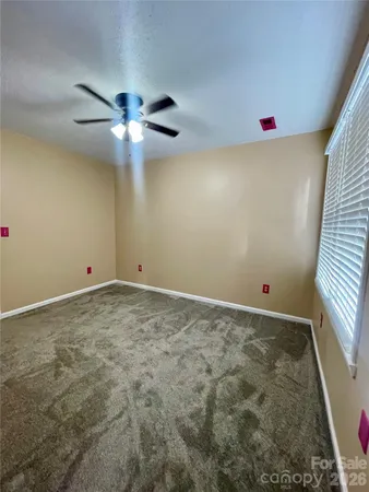 a view of an empty room with chandelier fan and fire place