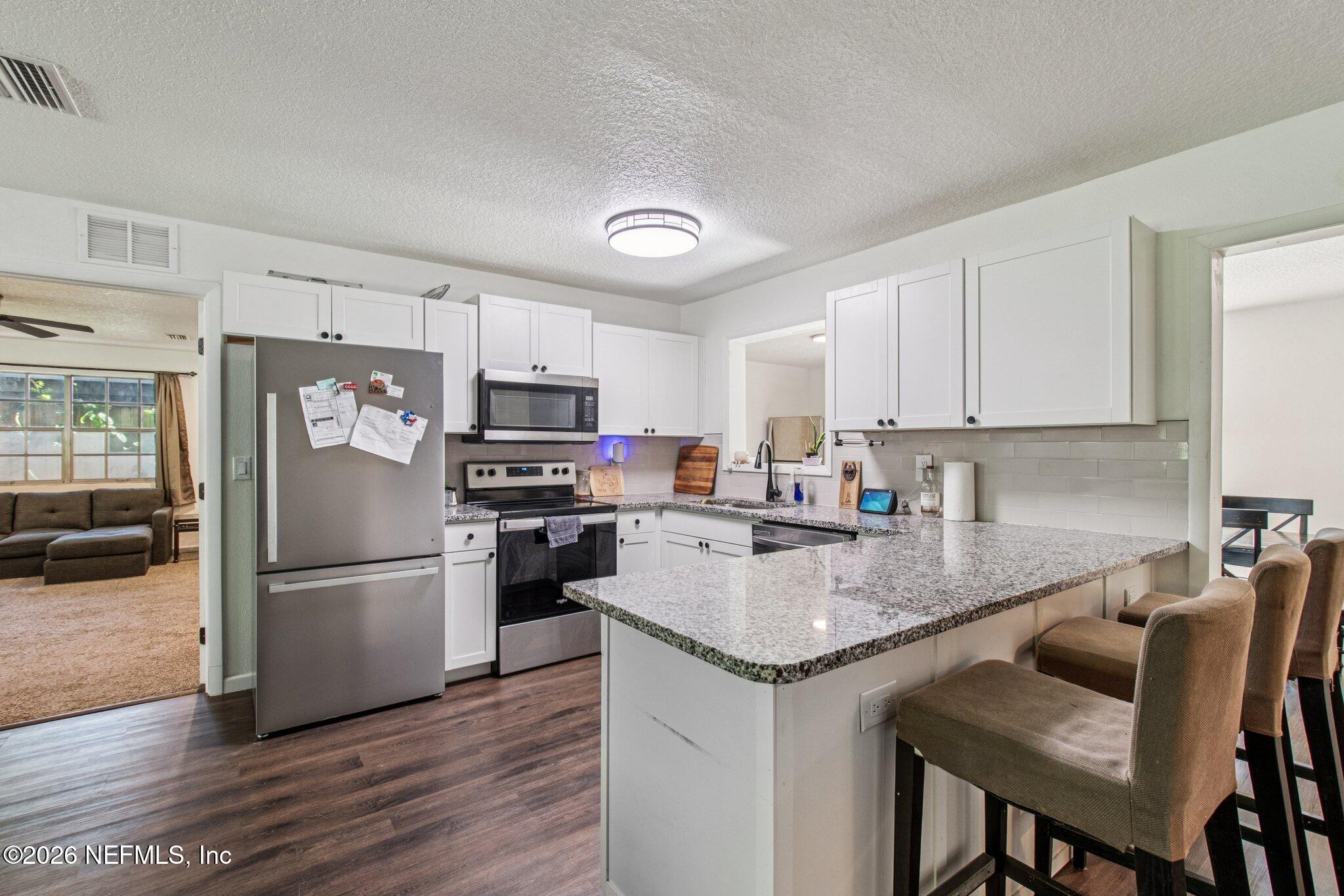 1417 Clock Street Jacksonville, FL 32211 - Photo 15 of 39 a kitchen with stainless steel appliances granite countertop a refrigerator a stove a sink a dining table and chairs